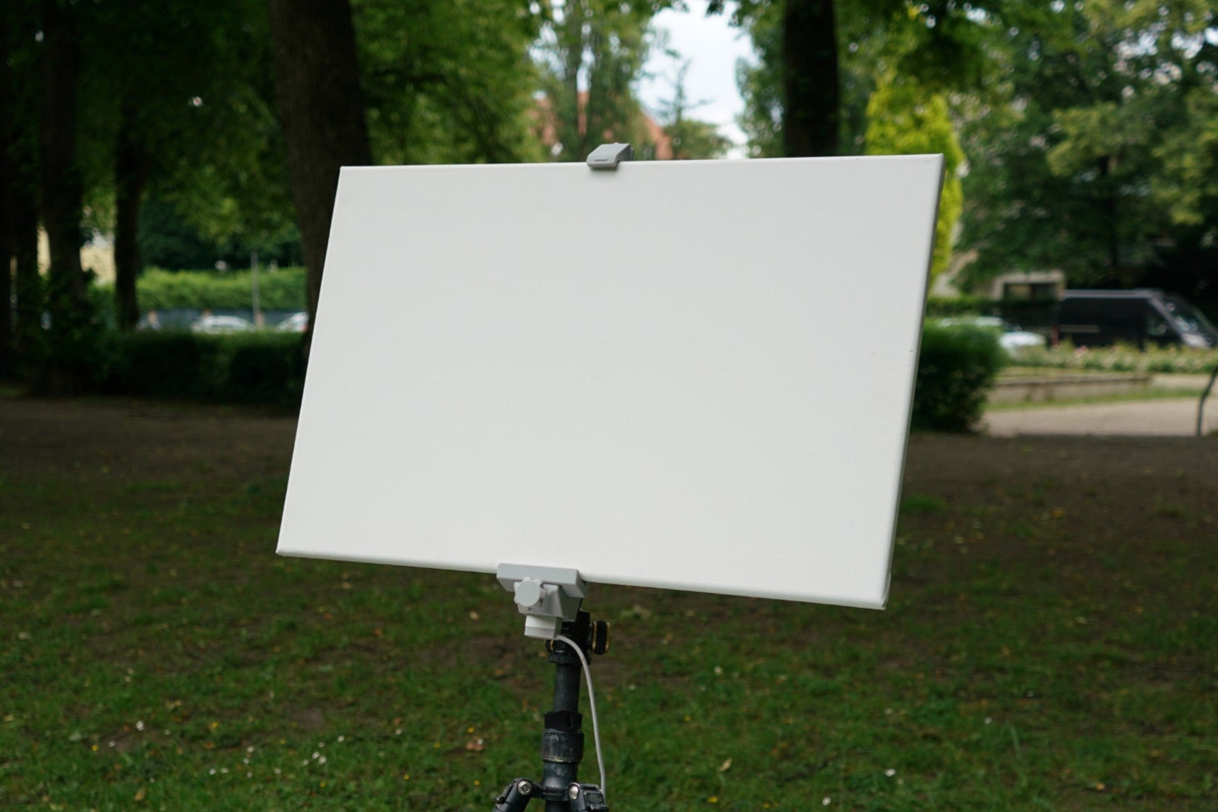 Easel with a blank canvas outdoors on a grassy area